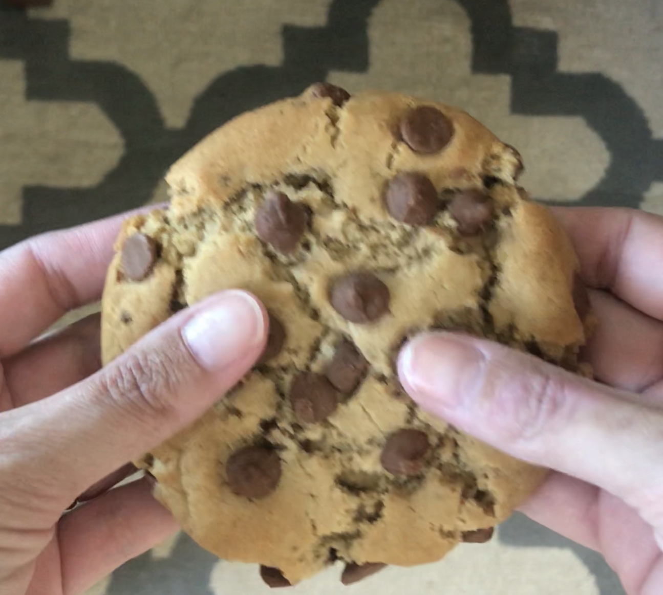 Cookie com gotas de chocolate segurado nas mãos